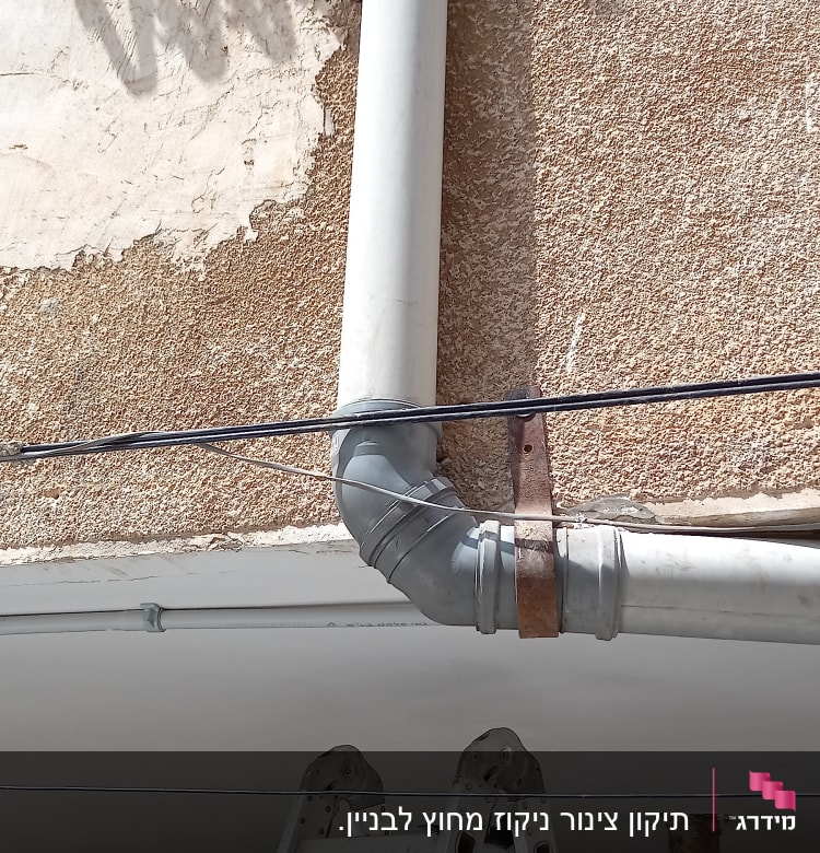 סולם ליד צינור ביוב חיצוני על קיר בניין